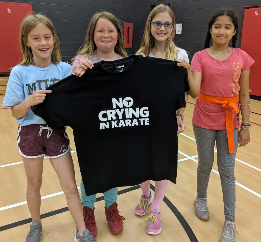 4 girls holding a "no crying in karate" t-shirt